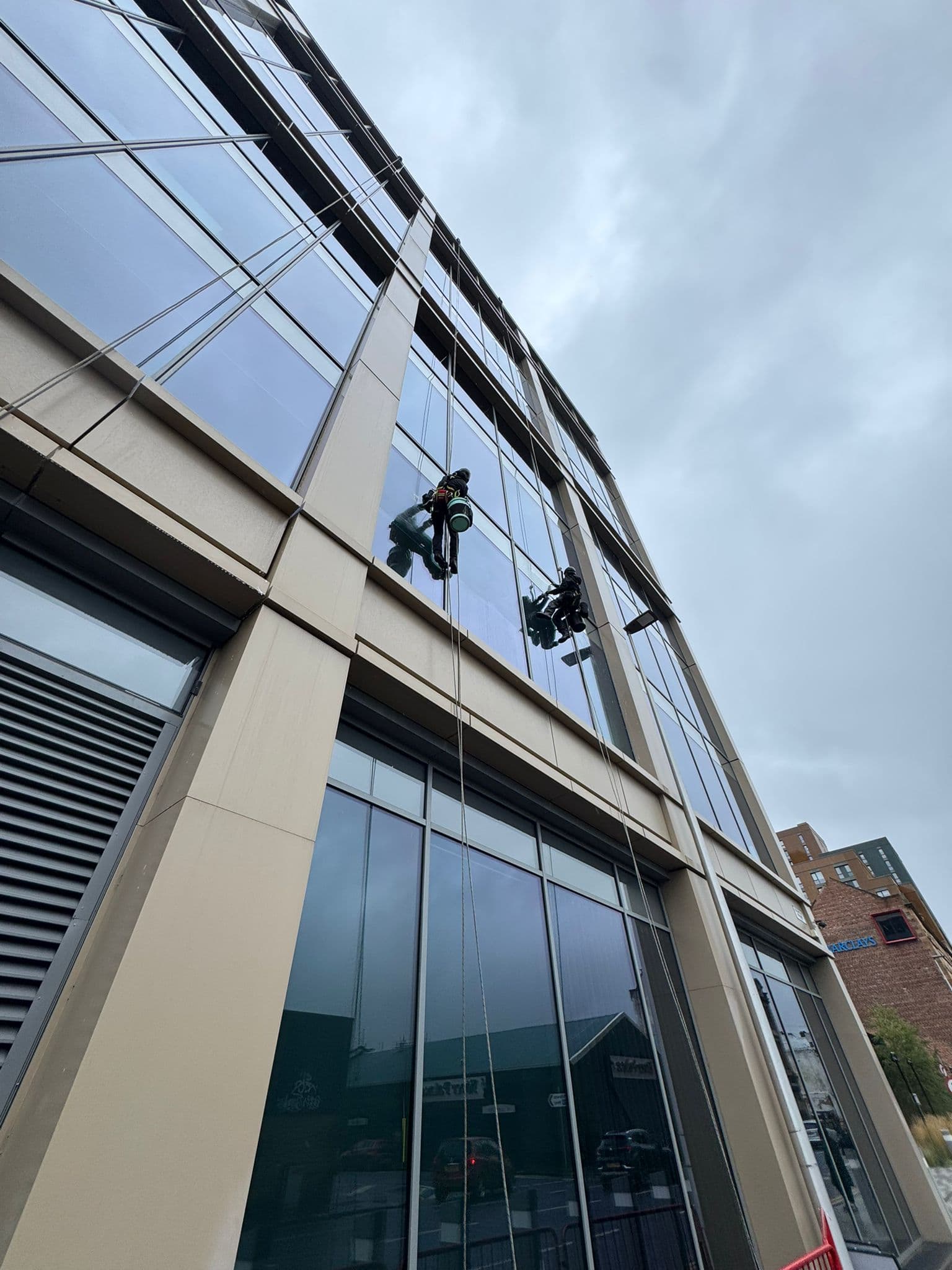 IRATA rope access technicians cleaning Barclays Bank Complex high-rise glass facade in Glasgow